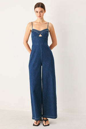 Woman wearing a blue denim jumpsuit featuring cami top with cut out, wide leg and back zipper closure | FREEMARKET