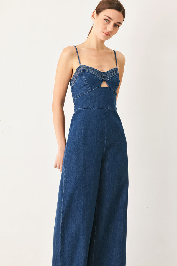 Woman wearing a blue denim jumpsuit featuring cami top with cut out, wide leg and back zipper closure | FREEMARKET