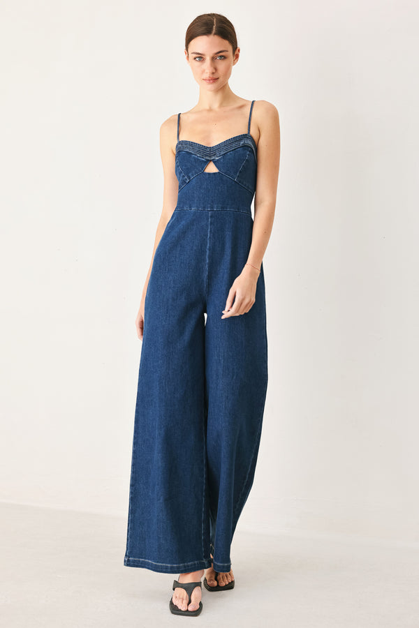 Woman wearing a blue denim jumpsuit featuring cami top with cut out, wide leg and back zipper closure | FREEMARKET