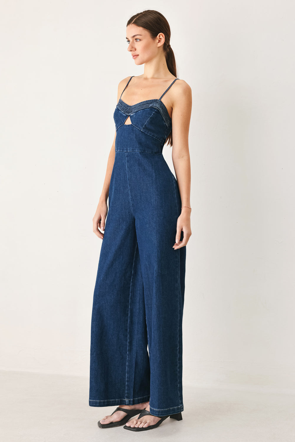 Woman wearing a blue denim jumpsuit featuring cami top with cut out, wide leg and back zipper closure | FREEMARKET