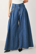 Woman wearing a pair of extra wide-leg blue denim jeans with front closure, pockets, pleats, and chain detail | FREEMARKET