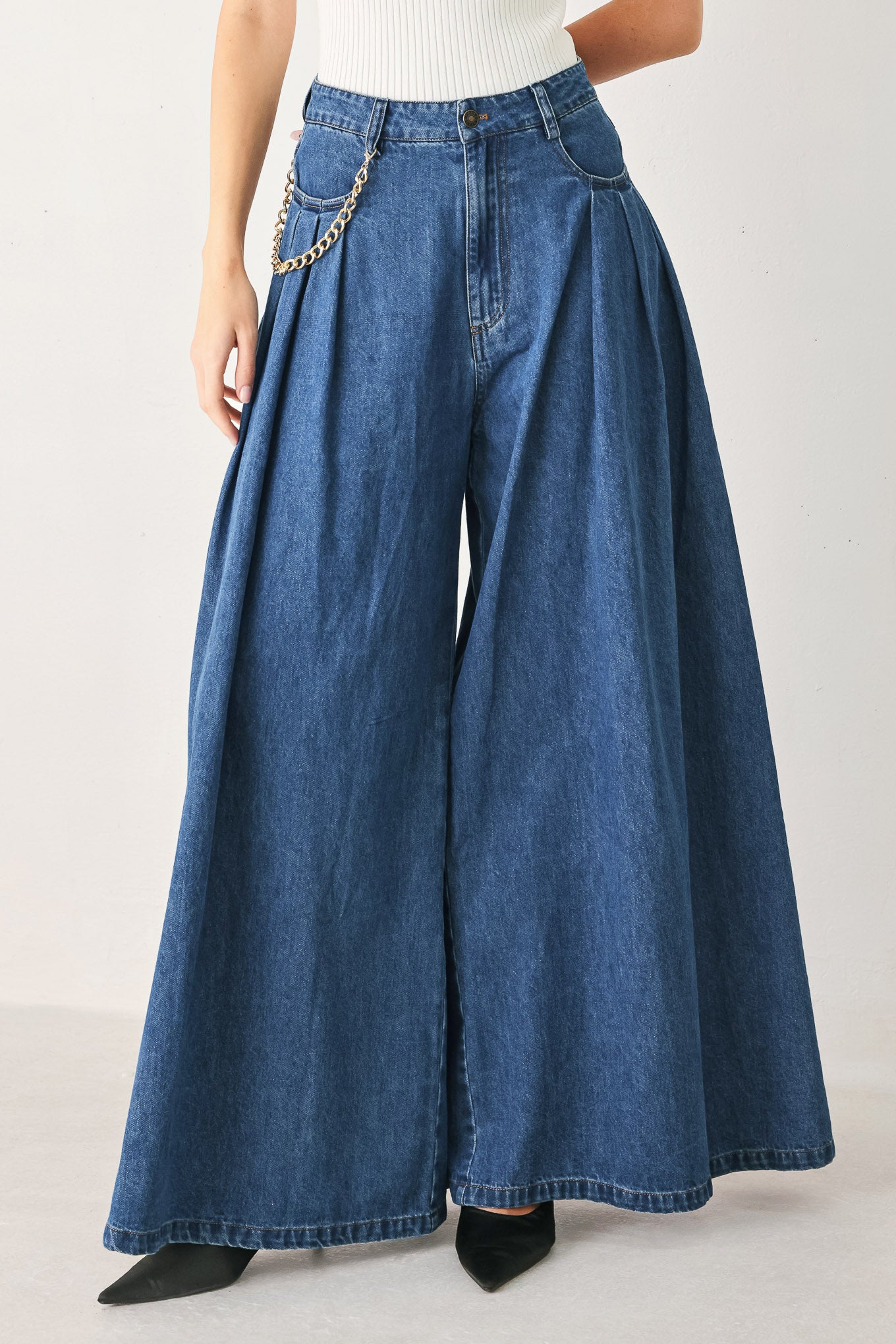 Person wearing a pair of wide-leg blue jeans on a plain background