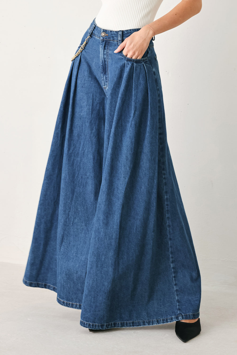Woman wearing a pair of extra wide-leg blue denim jeans with front closure, pockets, pleats, and chain detail | FREEMARKET