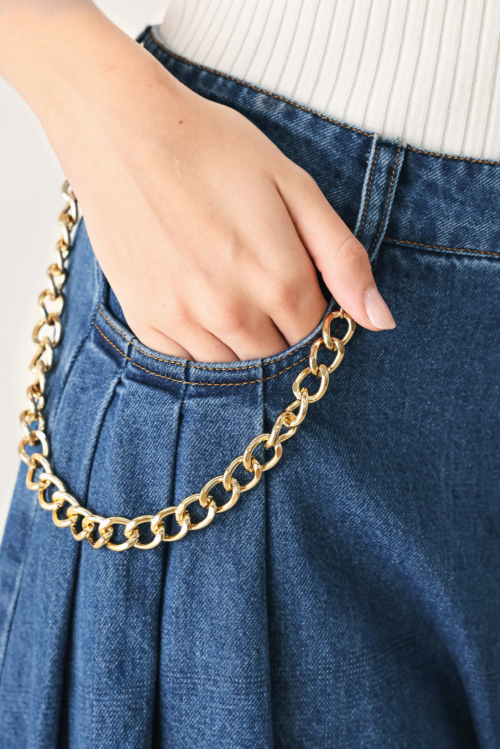 Woman wearing a pair of extra wide-leg blue denim jeans with front closure, pockets, pleats, and chain detail | FREEMARKET