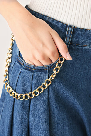 Woman wearing a pair of extra wide-leg blue denim jeans with front closure, pockets, pleats, and chain detail | FREEMARKET