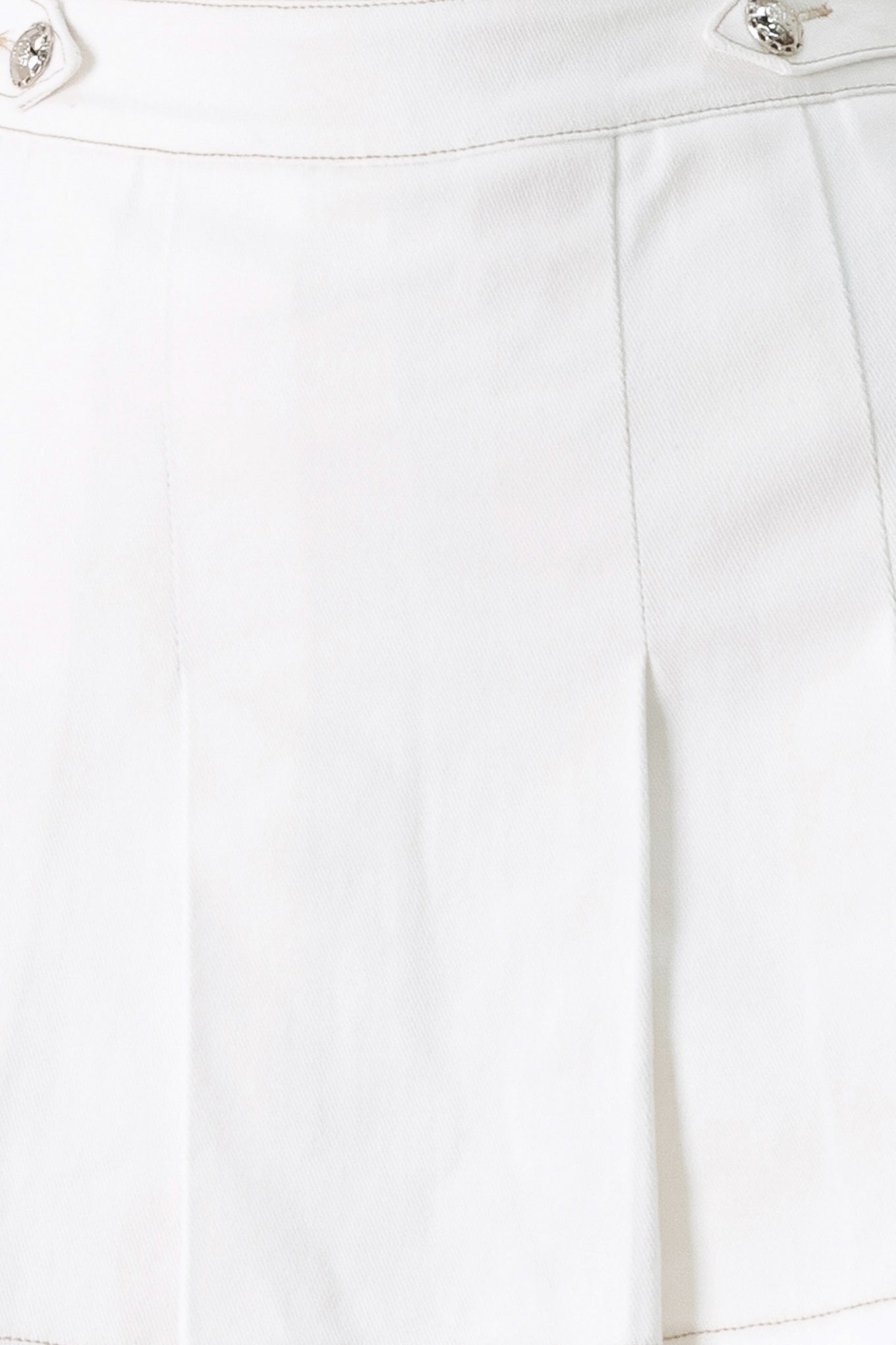 Woman wearing a white pleated skort with a button on each side of the waistband | FREEMARKET