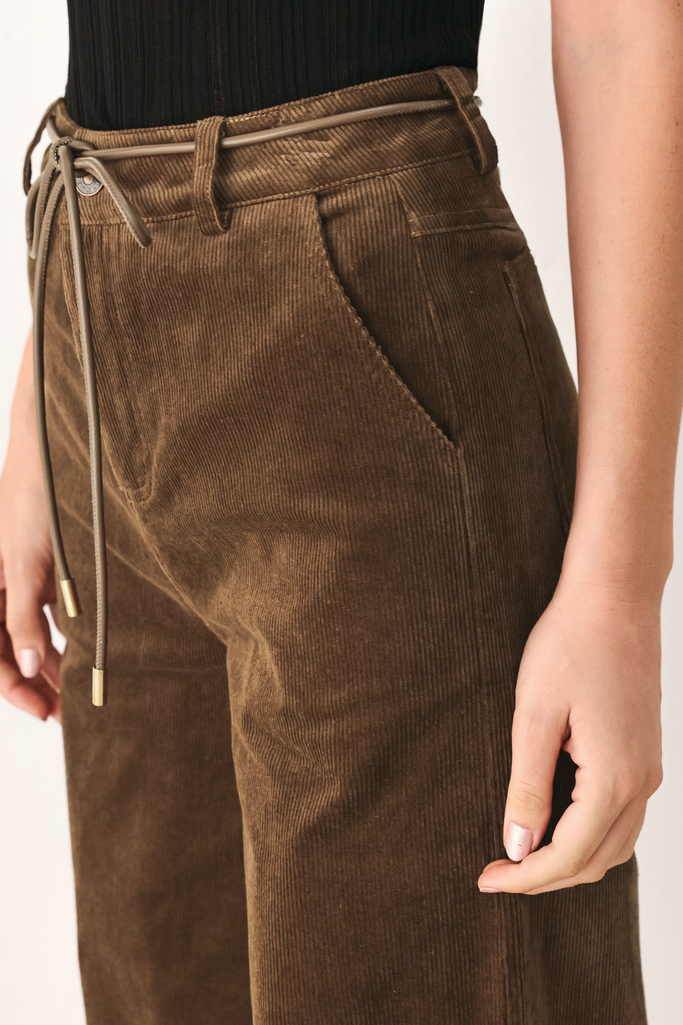 A model wearing high-waisted, wide-leg brown corduroy pants with a drawstring waist | FREEMARKET