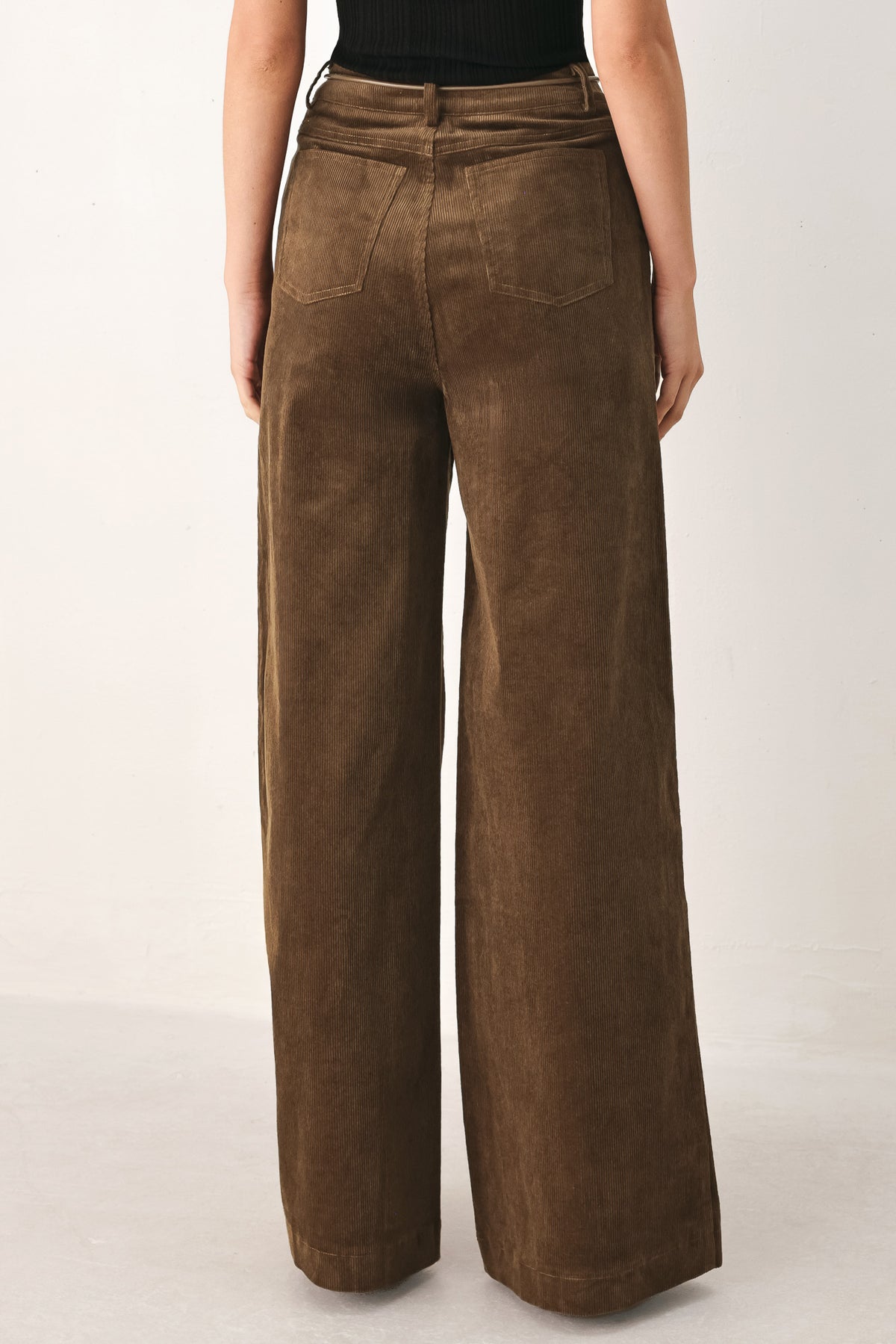 A model wearing high-waisted, wide-leg brown corduroy pants with a drawstring waist | FREEMARKET