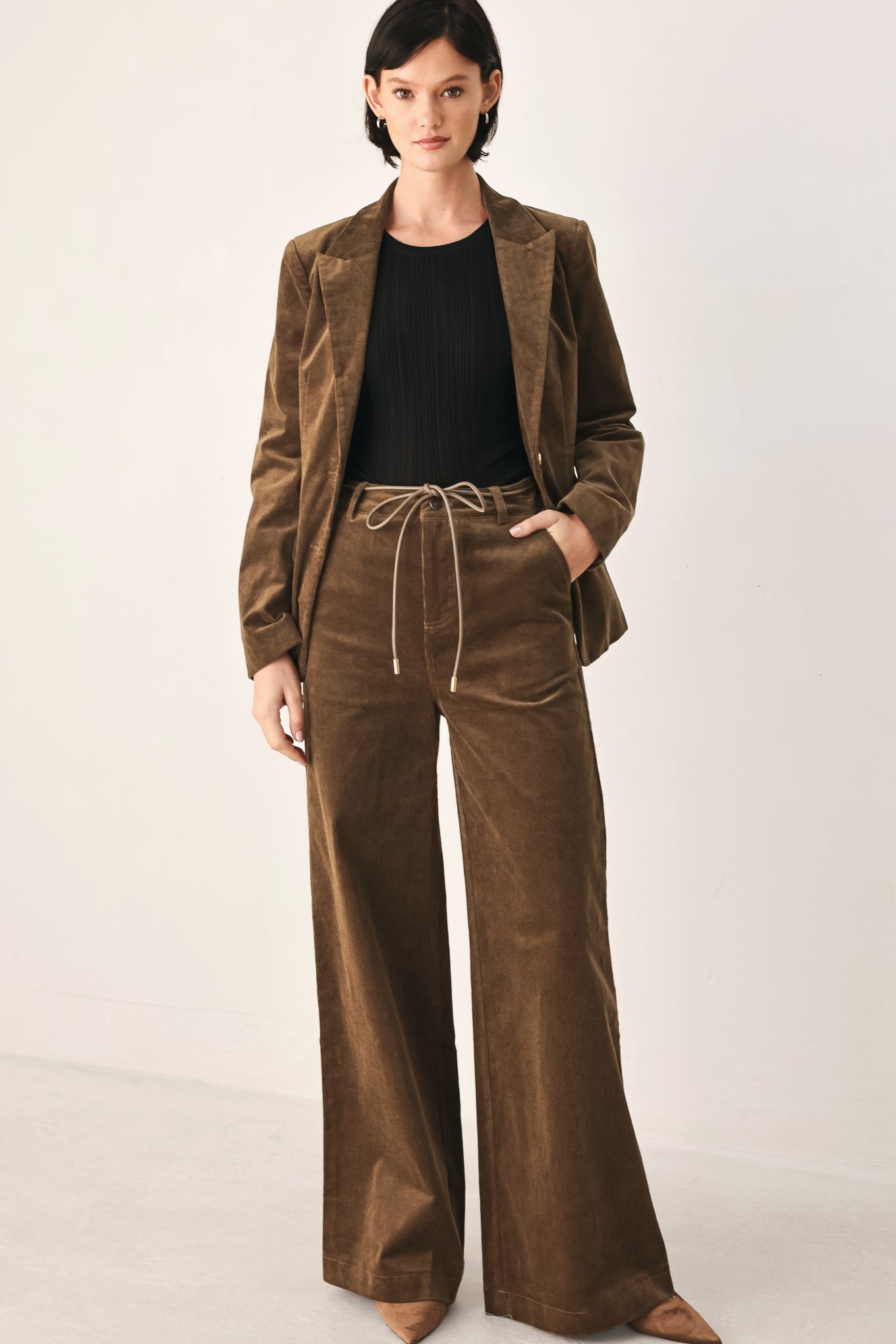 A model wearing high-waisted, wide-leg brown corduroy pants with a drawstring waist | FREEMARKET