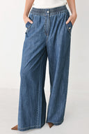 A person wearing wide-leg blue denim jeans with an elastic waistband, side pockets, and a button closure | FREEMARKET