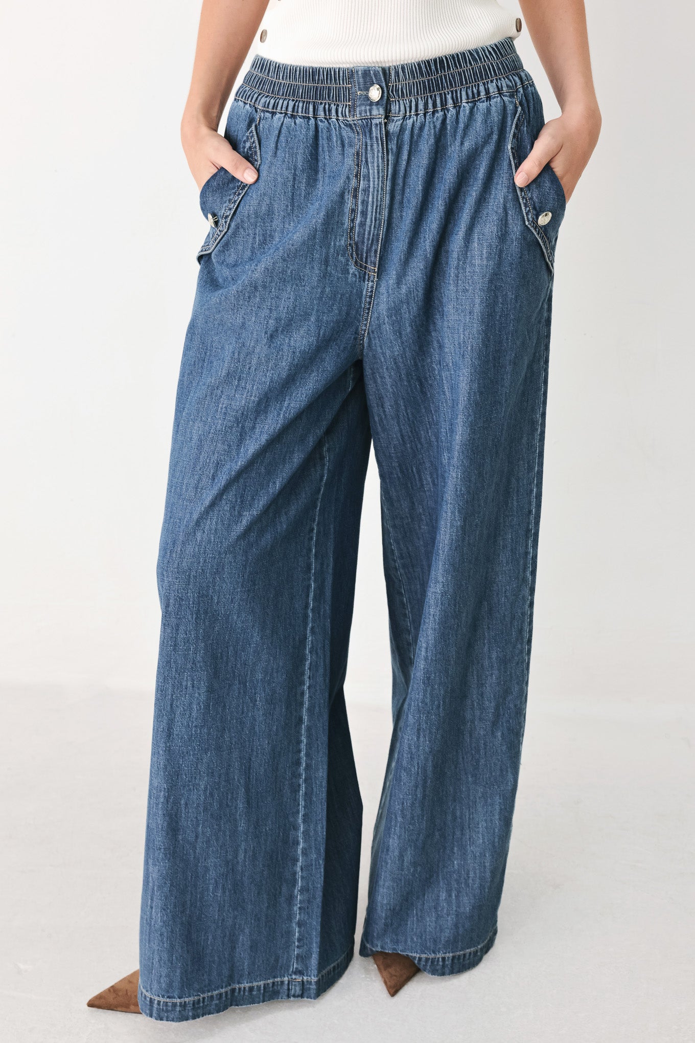 A person wearing wide-leg blue denim jeans with an elastic waistband, side pockets, and a button closure | FREEMARKET