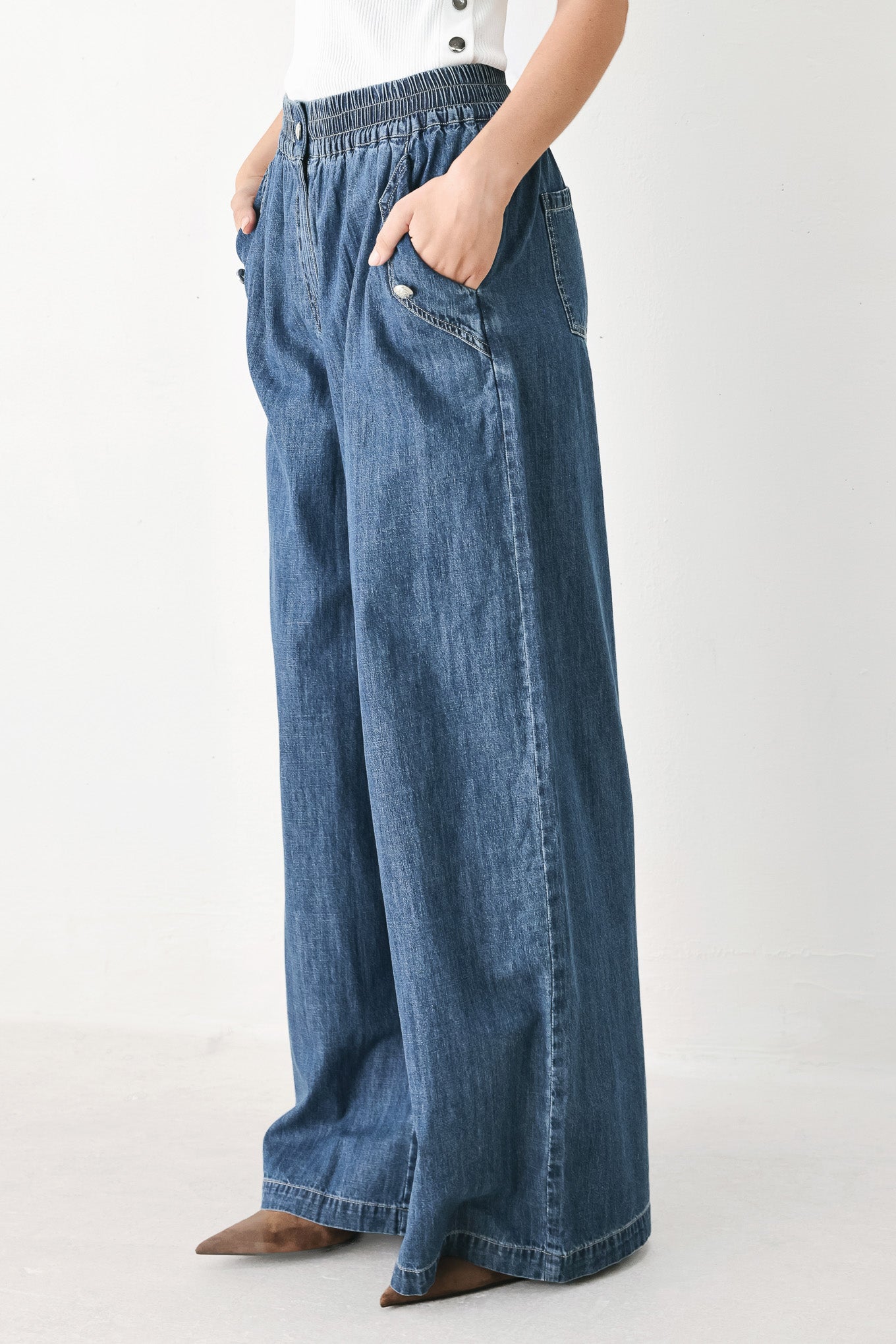 A person wearing wide-leg blue denim jeans with an elastic waistband, side pockets, and a button closure | FREEMARKET