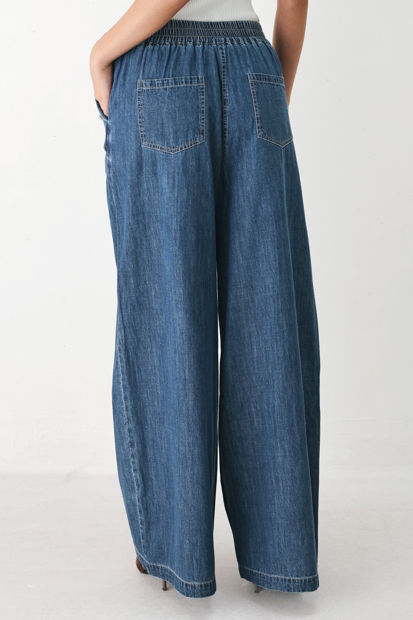 A person wearing wide-leg blue denim jeans with an elastic waistband, side pockets, and a button closure | FREEMARKET