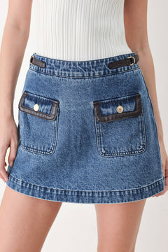 A model wearing a blue denim mini skort with dark brown leather accents on the waistband and pocket flaps | FREEMARKET