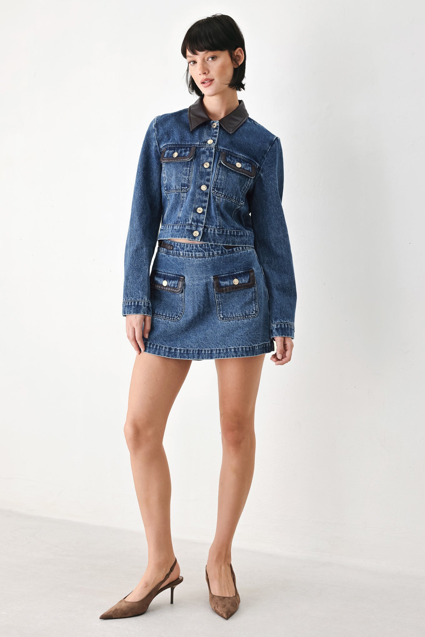 A model wearing a blue denim mini skort with dark brown leather accents on the waistband and pocket flaps | FREEMARKET