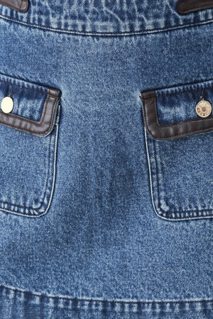 A model wearing a blue denim mini skort with dark brown leather accents on the waistband and pocket flaps | FREEMARKET