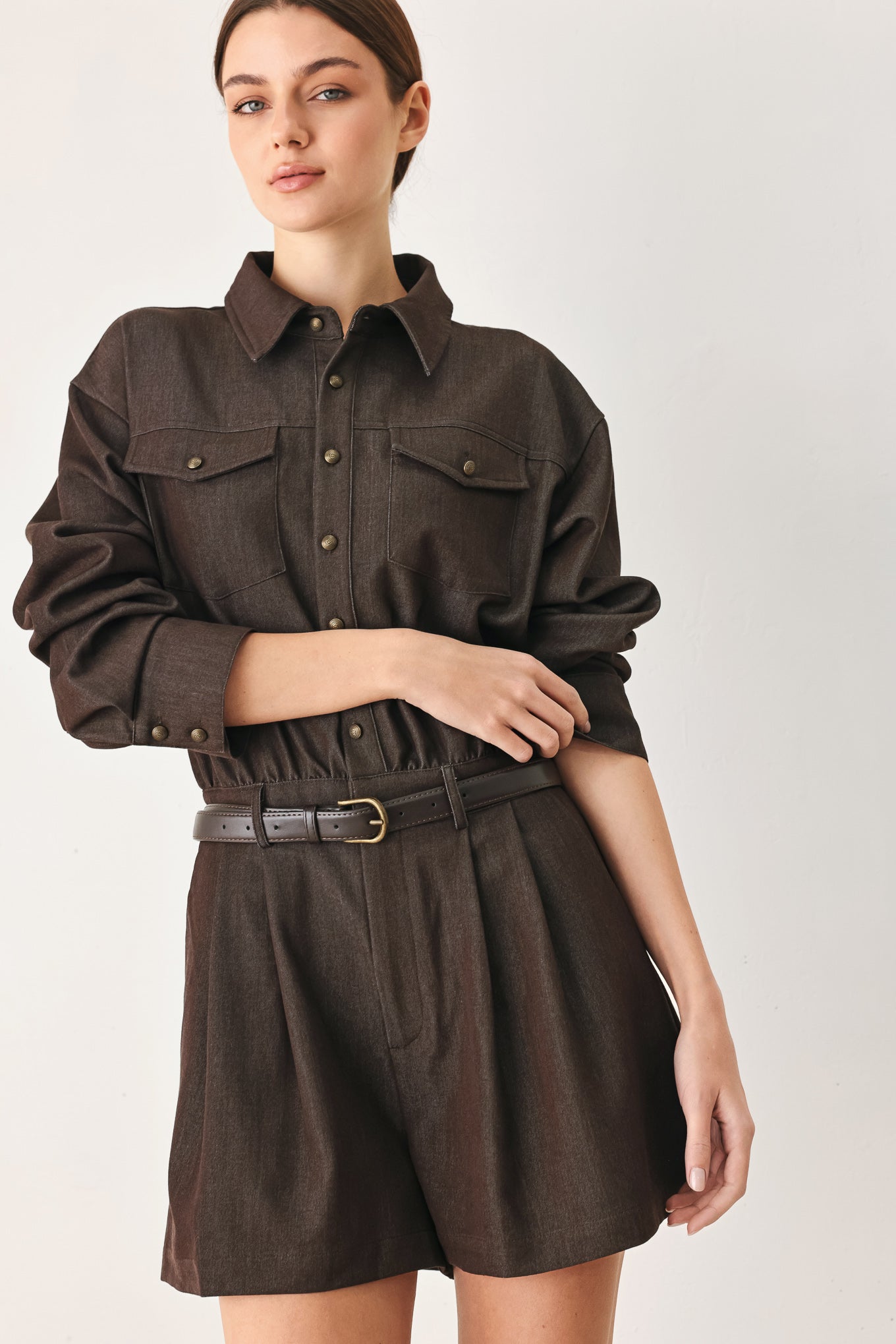 Woman wearing a brown woven romper featuring front button zipper closure, pockets, long sleeves and contrasting belt | FREEMARKET