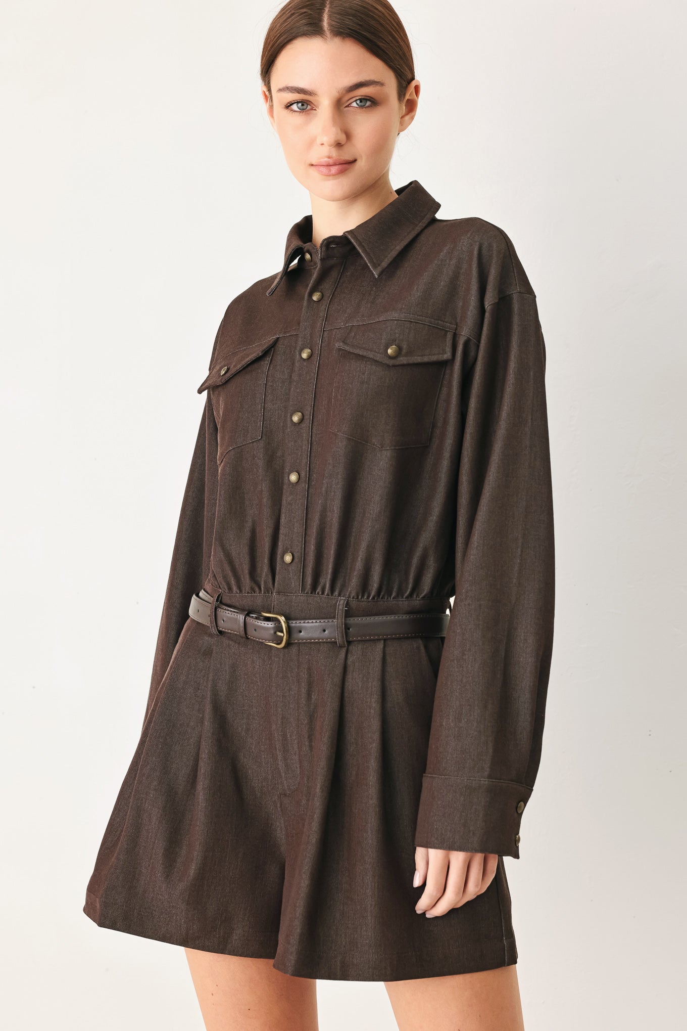 Woman wearing a brown woven romper featuring front button zipper closure, pockets, long sleeves and contrasting belt | FREEMARKET