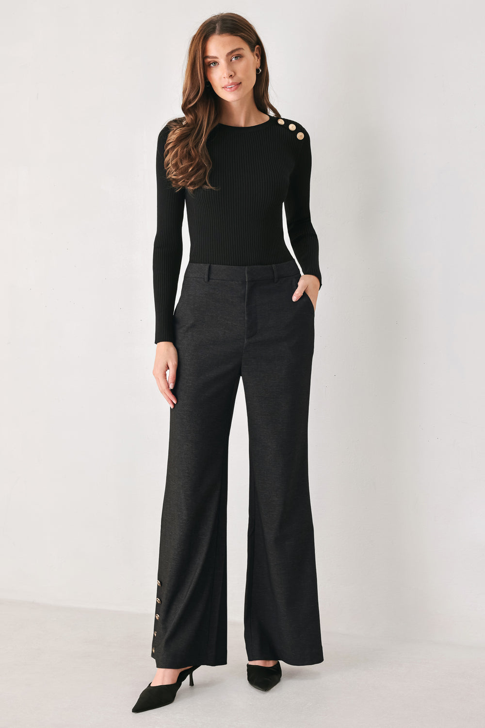 Woman wearing black high waisted pants with gold button details around the side calf | FREEMARKET