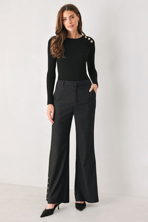 Woman wearing black high waisted pants with gold button details around the side calf | FREEMARKET