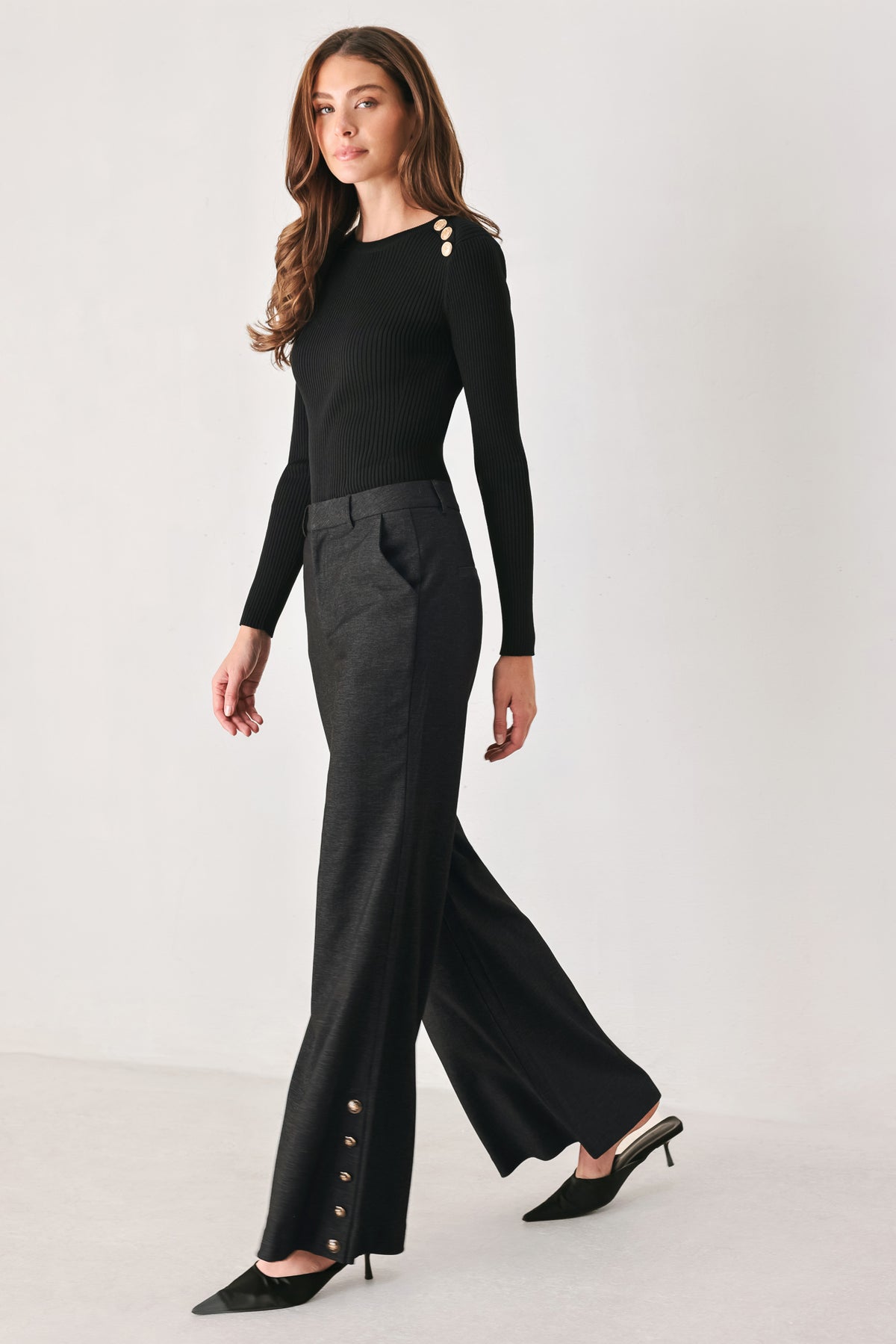 Woman wearing black high waisted pants with gold button details around the side calf | FREEMARKET