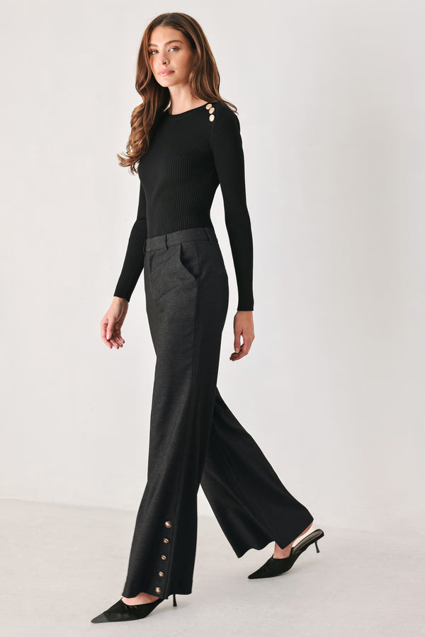 Woman wearing black high waisted pants with gold button details around the side calf | FREEMARKET