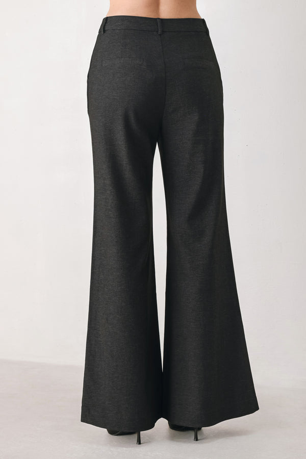 Woman wearing black high waisted pants with gold button details around the side calf | FREEMARKET