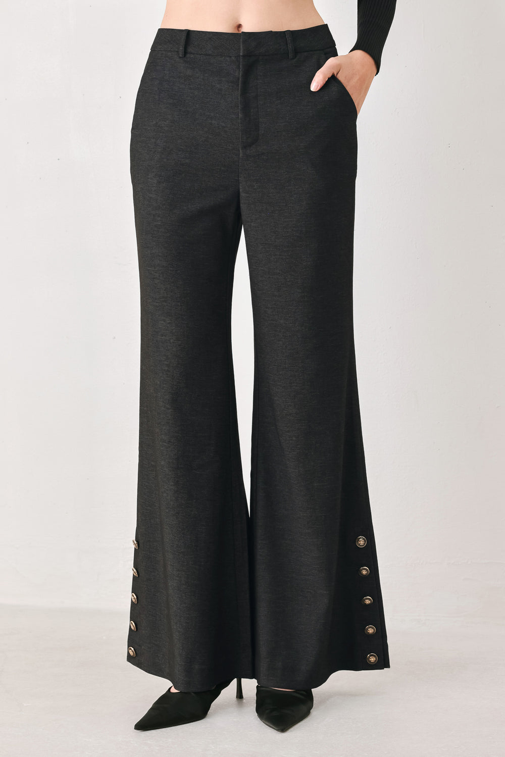 Woman wearing black high waisted pants with gold button details around the side calf | FREEMARKET