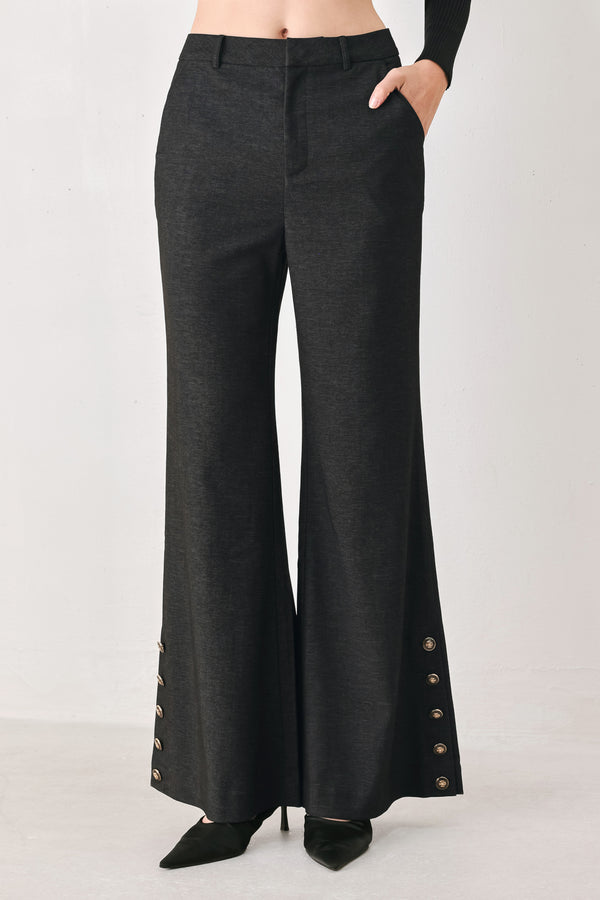 Woman wearing black high waisted pants with gold button details around the side calf | FREEMARKET