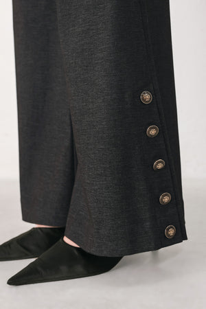 Woman wearing black high waisted pants with gold button details around the side calf | FREEMARKET