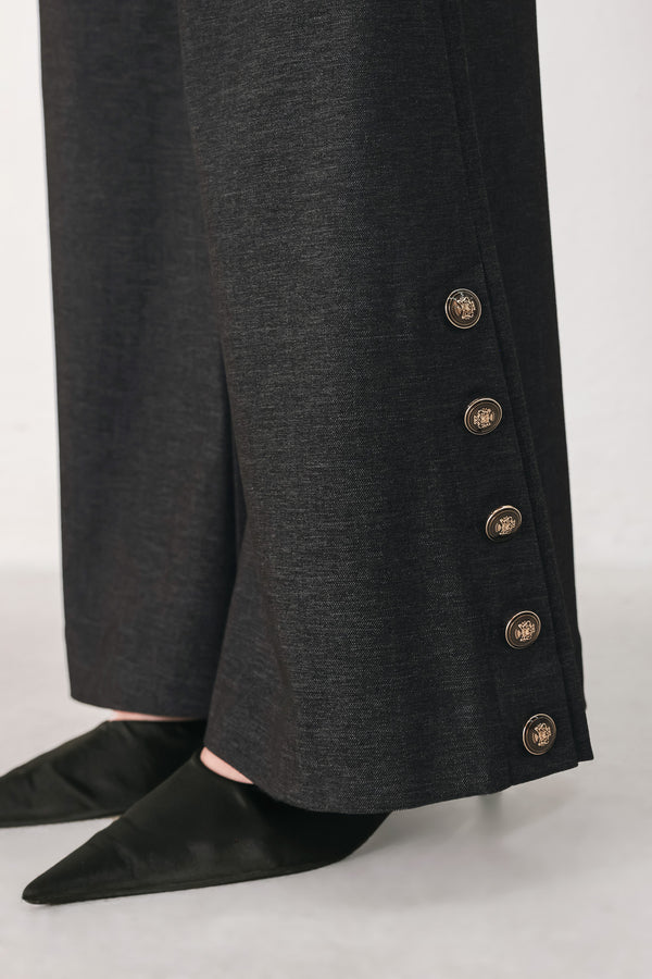 Woman wearing black high waisted pants with gold button details around the side calf | FREEMARKET
