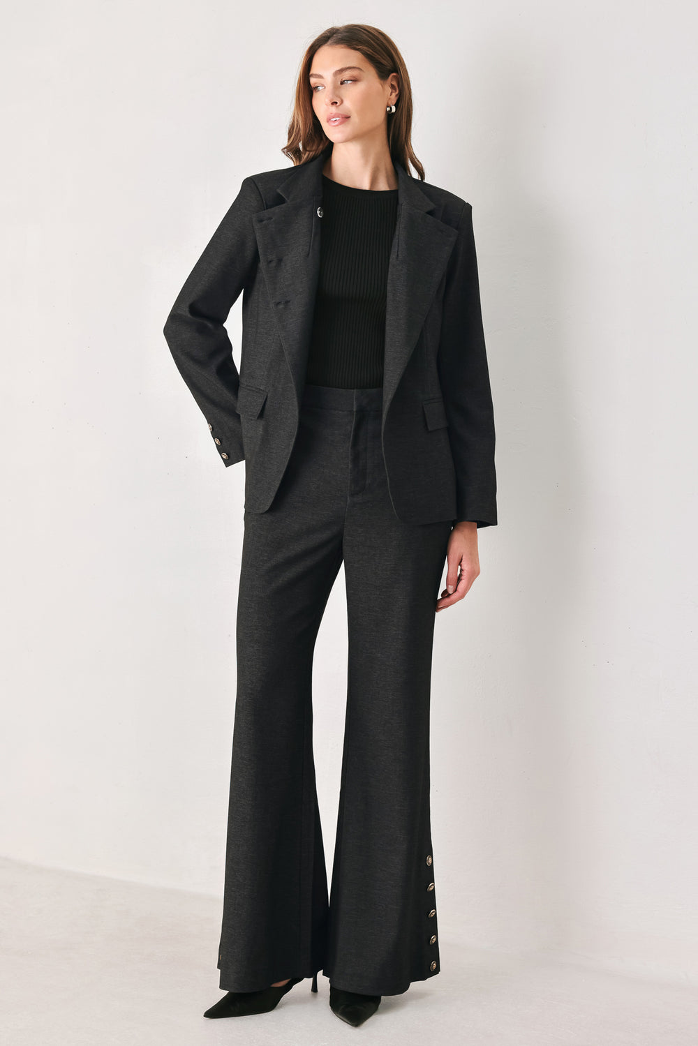 Woman wearing black high waisted pants with gold button details around the side calf | FREEMARKET