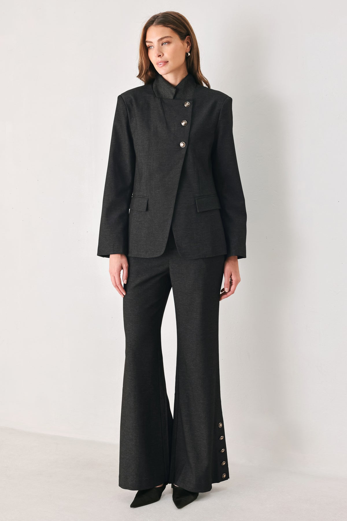 Woman wearing black high waisted pants with gold button details around the side calf | FREEMARKET