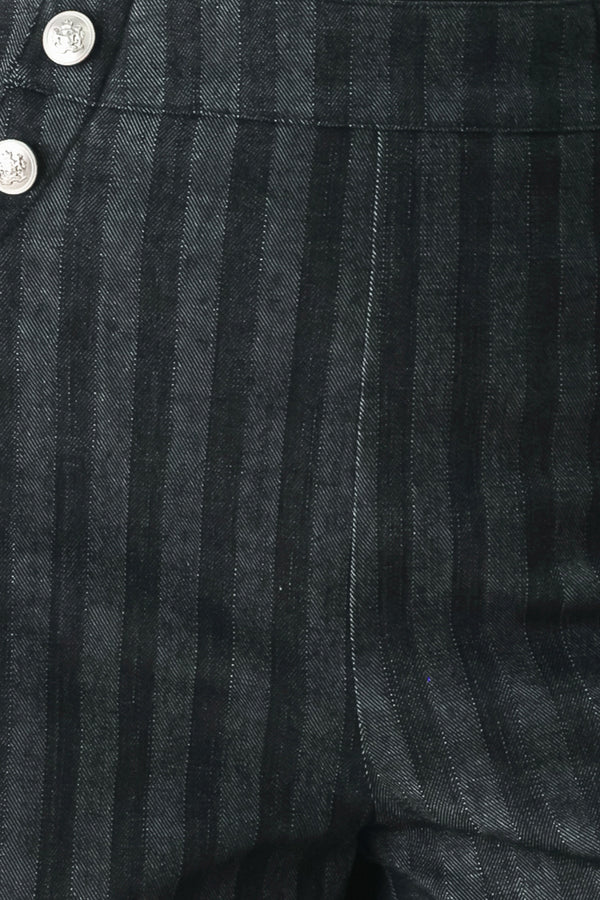 A model wearing a pair of high-waisted, wide-leg trousers in a dark gray and black pinstripe pattern, featuring decorative silver buttons on the front waistband | FREEMARKET