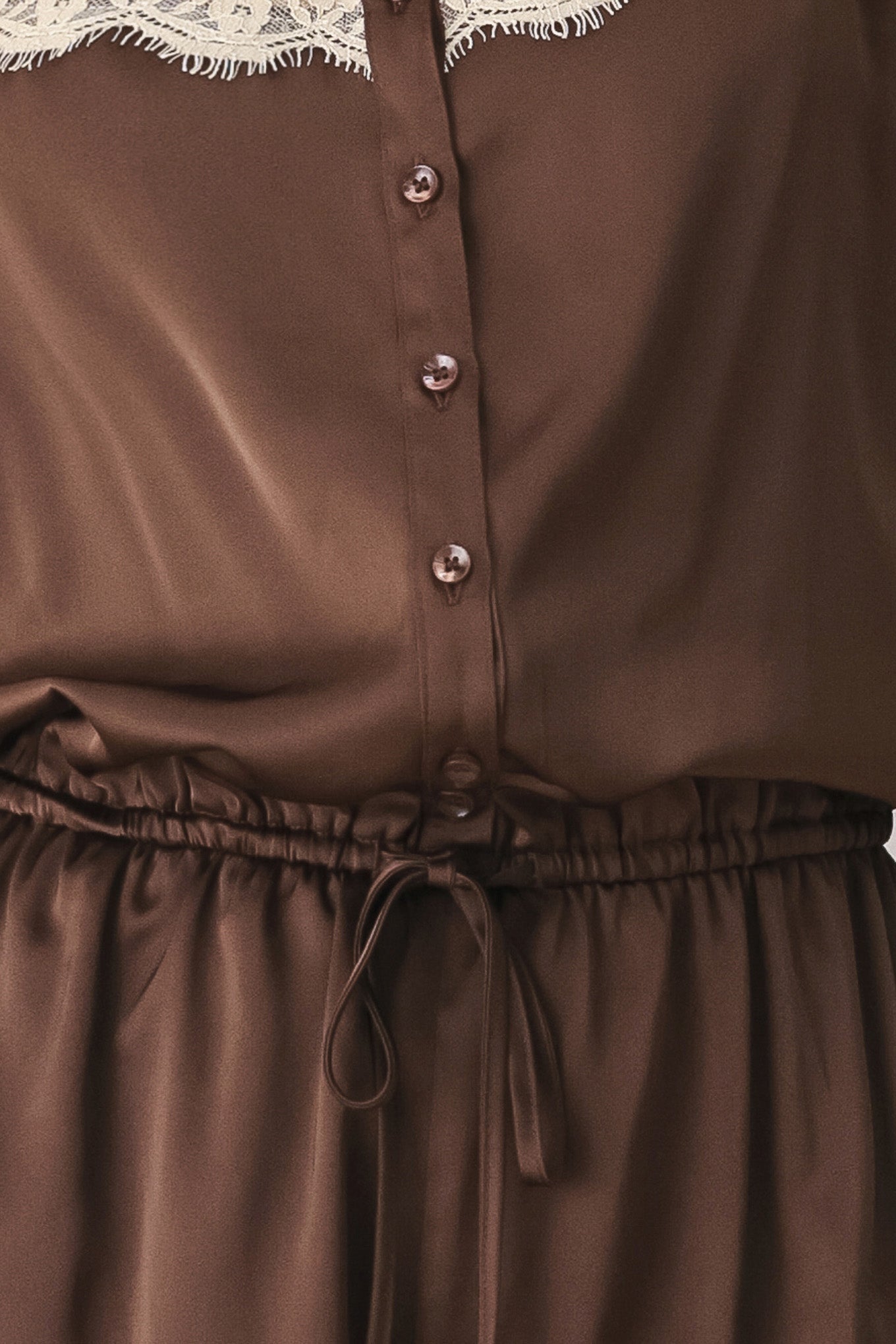 A woman wearing a brown satin romper with beige lace trim at the neckline | FREEMARKET