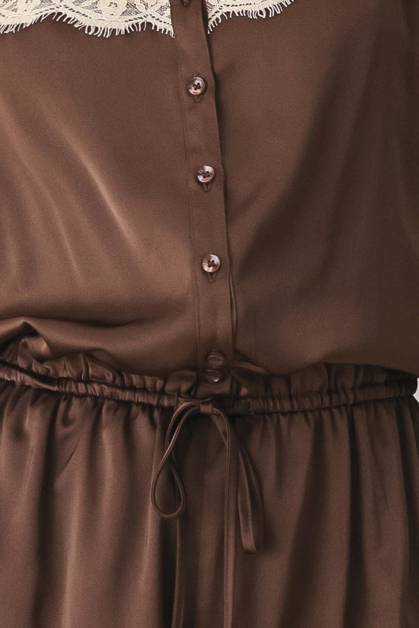 A woman wearing a brown satin romper with beige lace trim at the neckline | FREEMARKET