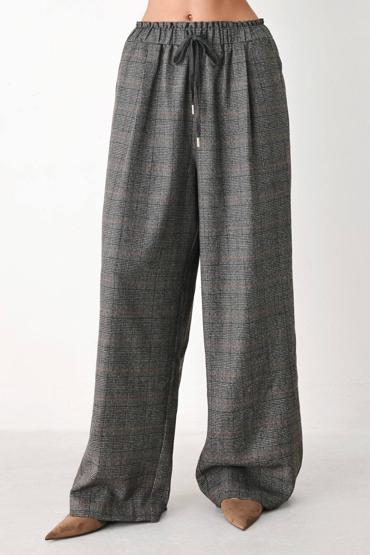 A person wearing loose, wide-leg plaid trousers in dark gray with subtle brown and beige lines, featuring an elastic drawstring waistband | FREEMARKET