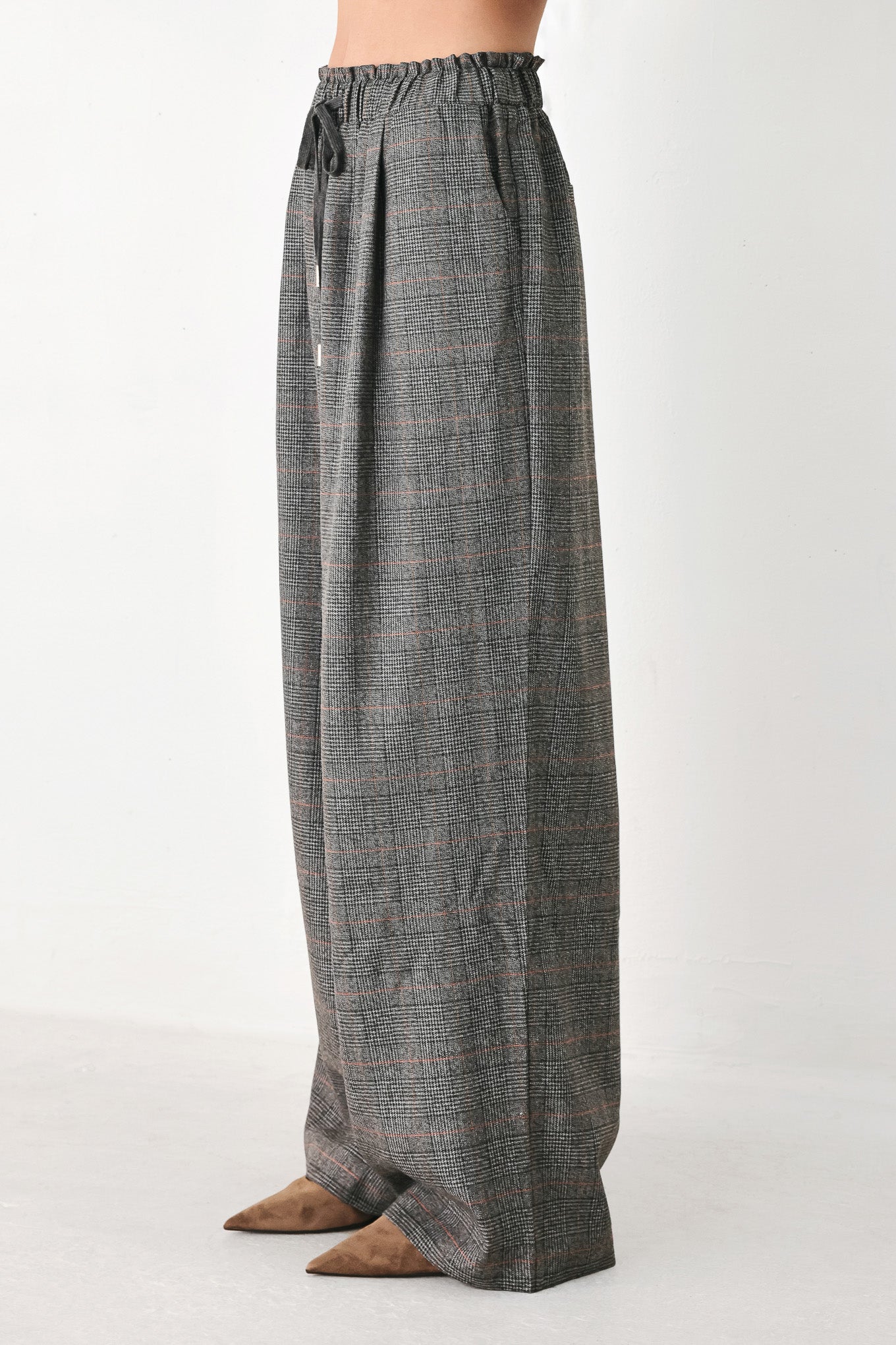 A person wearing loose, wide-leg plaid trousers in dark gray with subtle brown and beige lines, featuring an elastic drawstring waistband | FREEMARKET