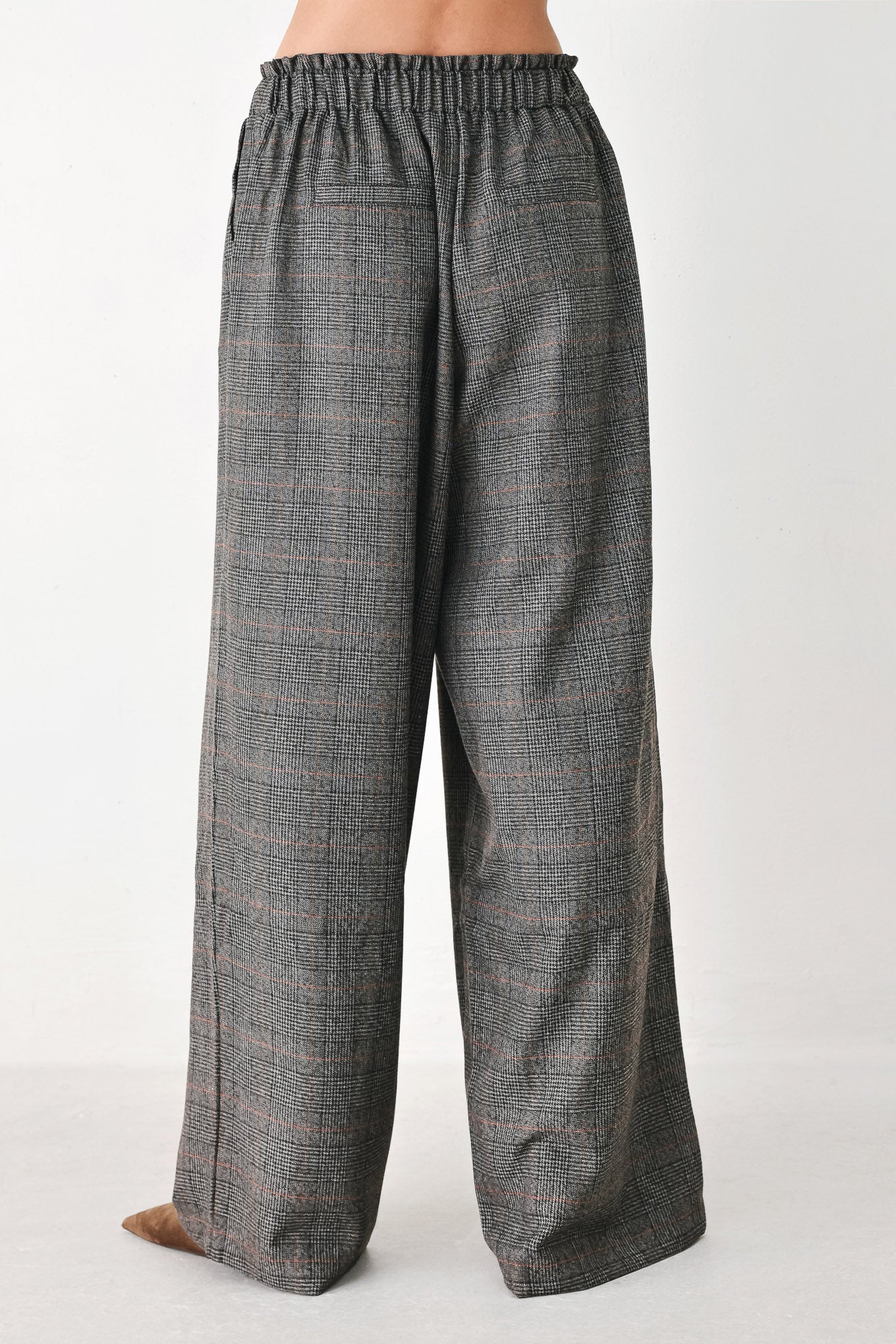 A person wearing loose, wide-leg plaid trousers in dark gray with subtle brown and beige lines, featuring an elastic drawstring waistband | FREEMARKET