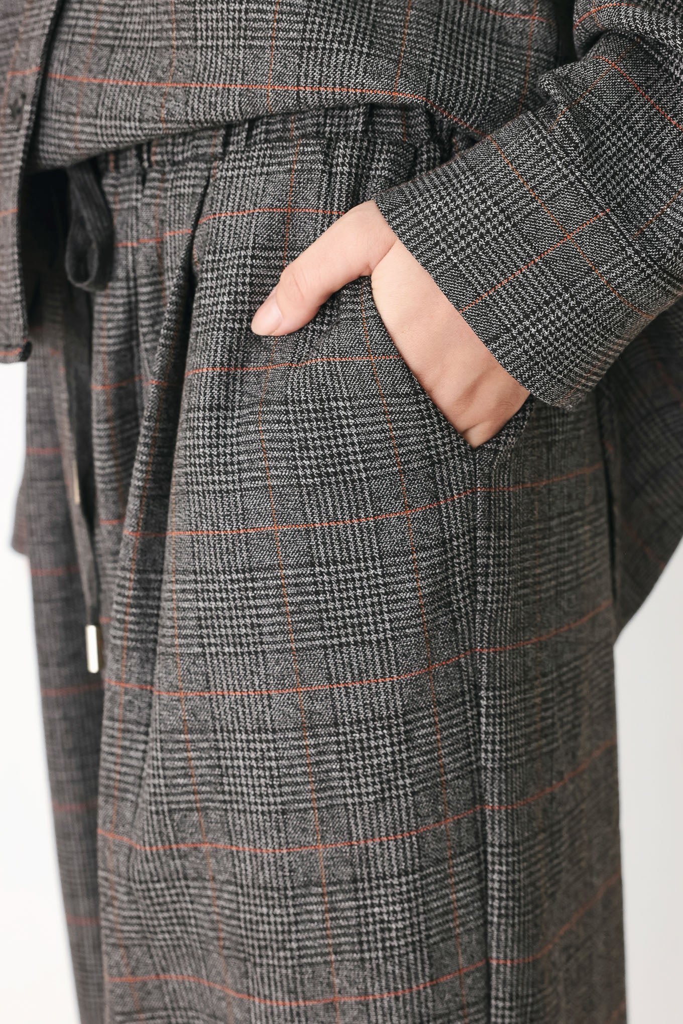 A person wearing loose, wide-leg plaid trousers in dark gray with subtle brown and beige lines, featuring an elastic drawstring waistband | FREEMARKET