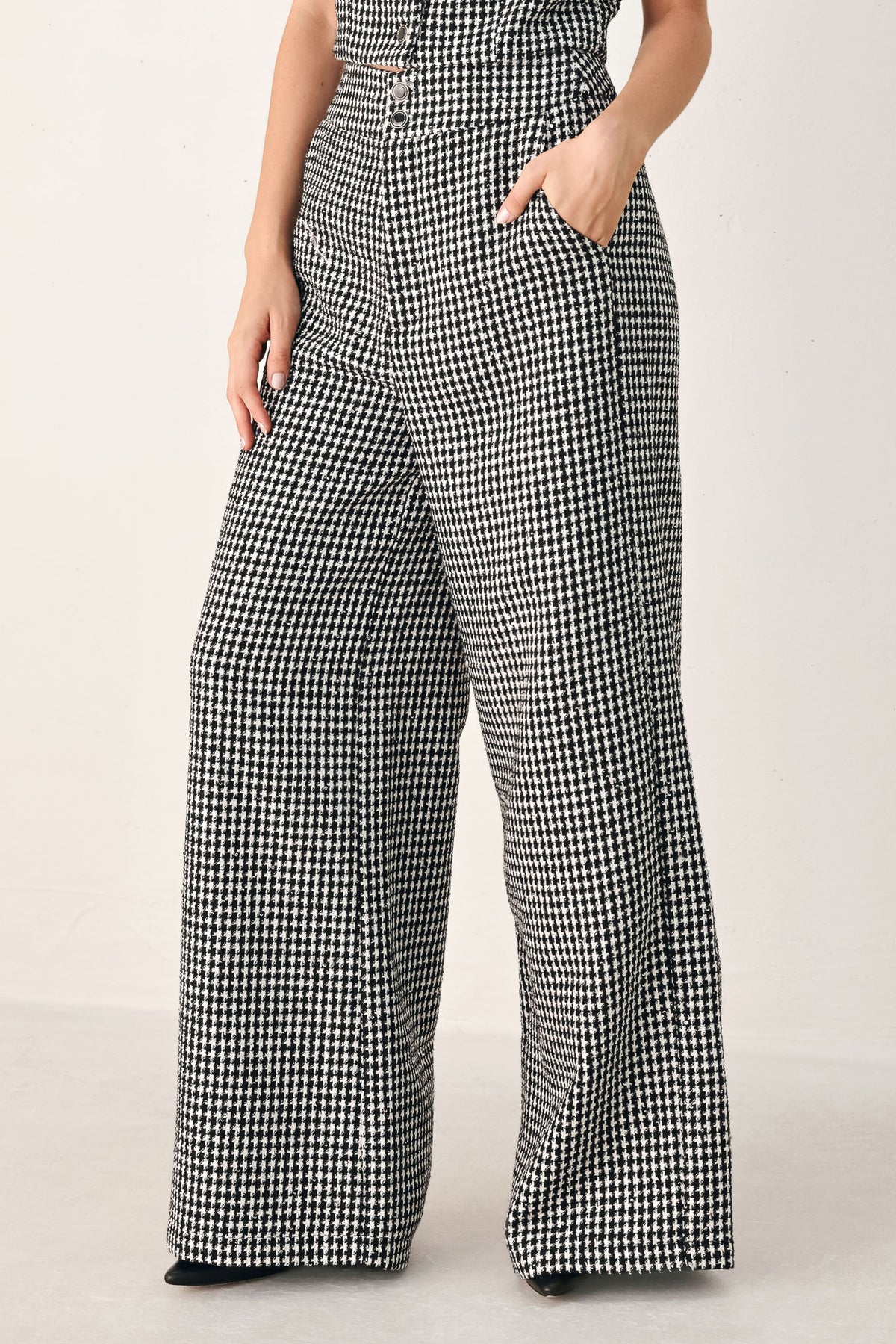 A person wearing high-waisted, wide-leg trousers with a black and white houndstooth pattern | FREEMARKET