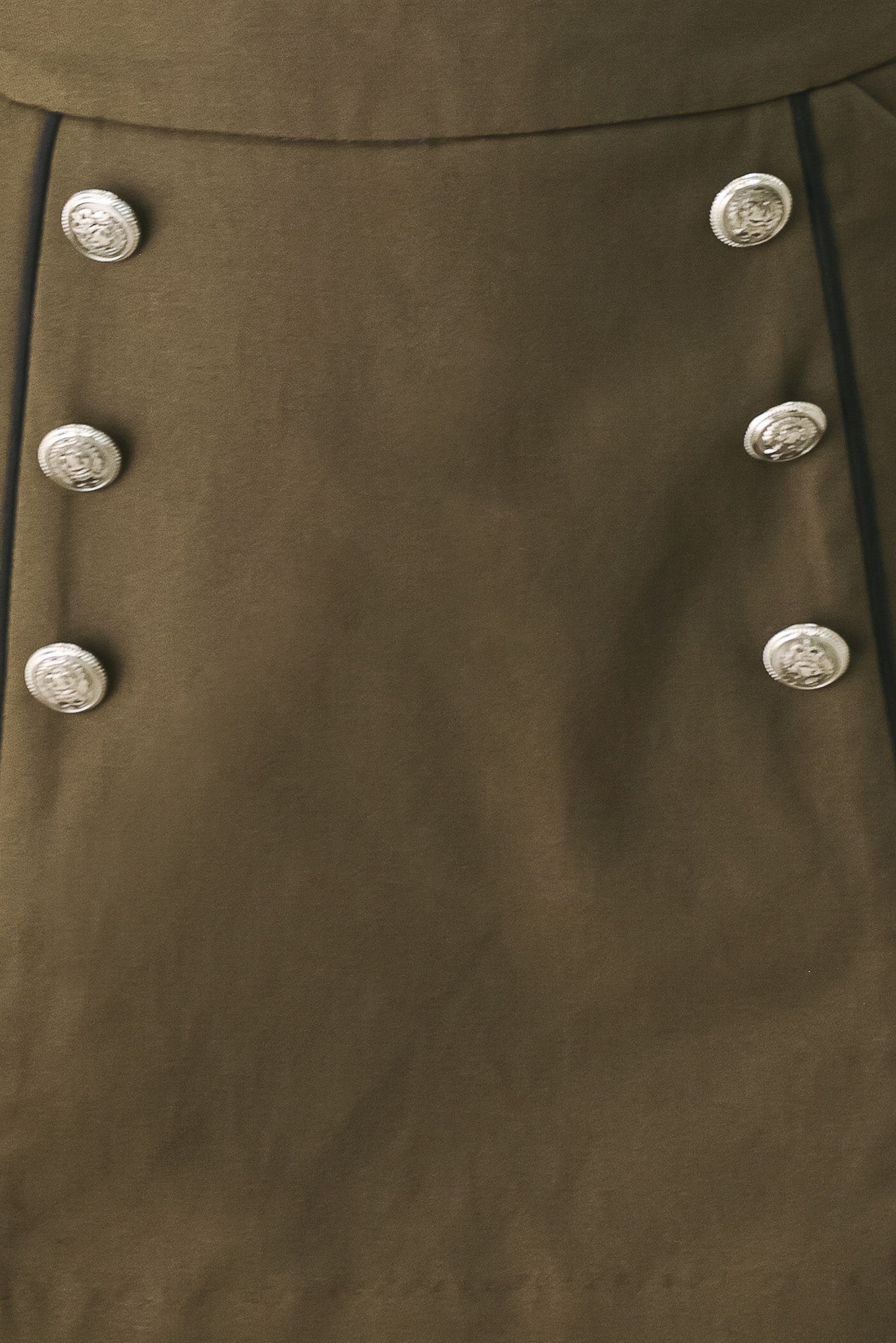 A woman wearing an olive green mini skort with double-breasted silver buttons | FREEMARKET
