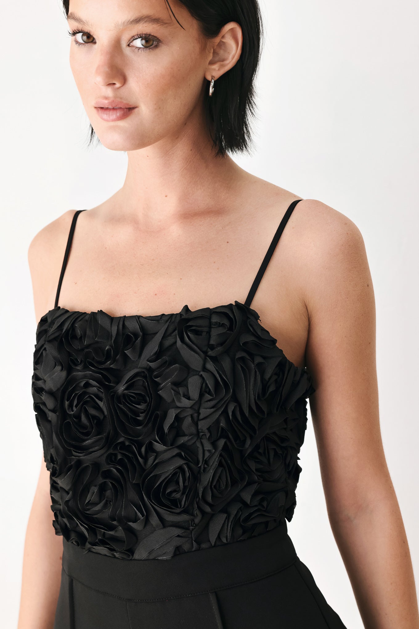 A woman modeling a black sleeveless jumpsuit with a textured floral bodice and wide-leg trousers | FREEMARKET