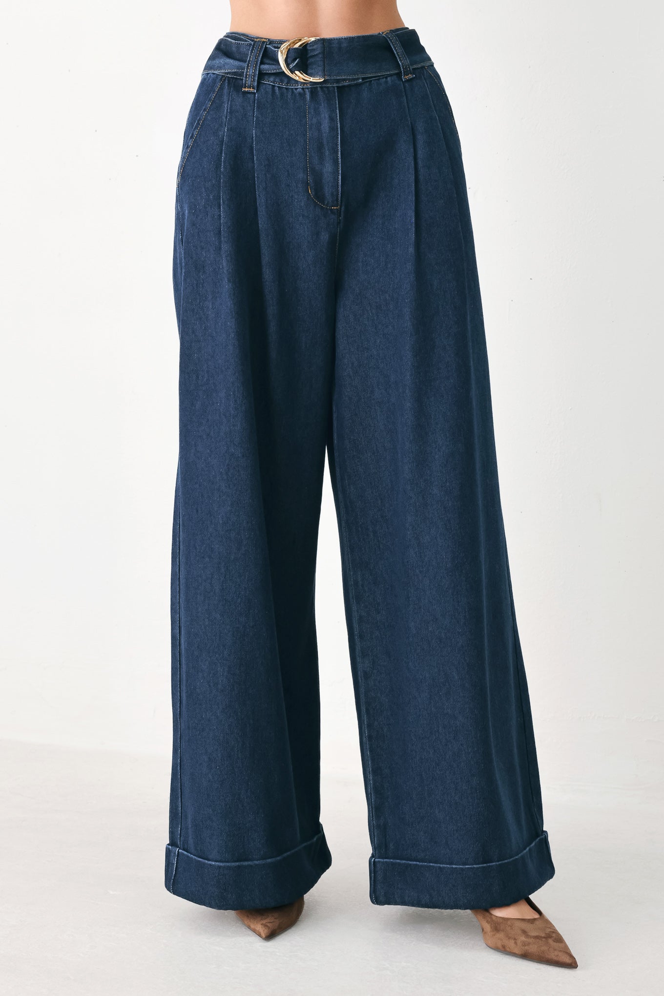 A person wearing dark blue wide-leg denim pants with a rolled cuff and a gold-tone belt buckle | FREEMARKET
