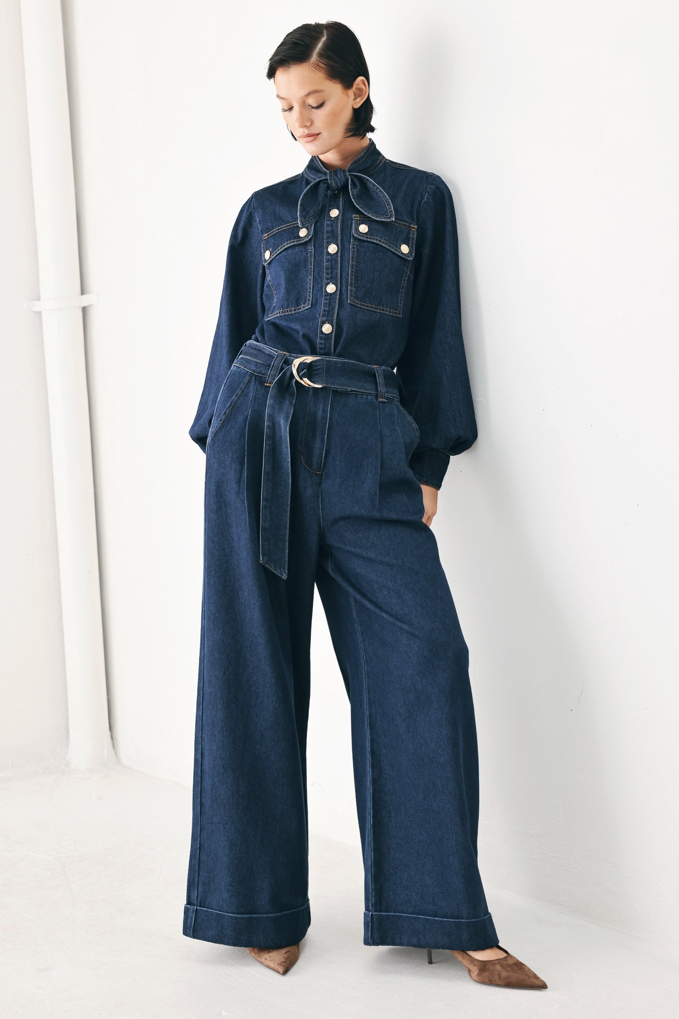 A person wearing dark blue wide-leg denim pants with a rolled cuff and a gold-tone belt buckle | FREEMARKET