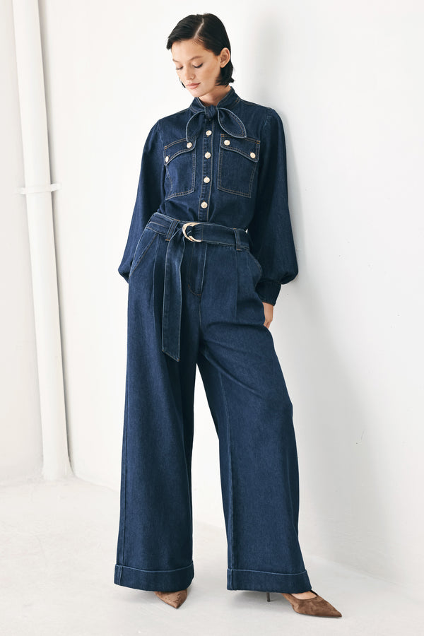 A person wearing dark blue wide-leg denim pants with a rolled cuff and a gold-tone belt buckle | FREEMARKET
