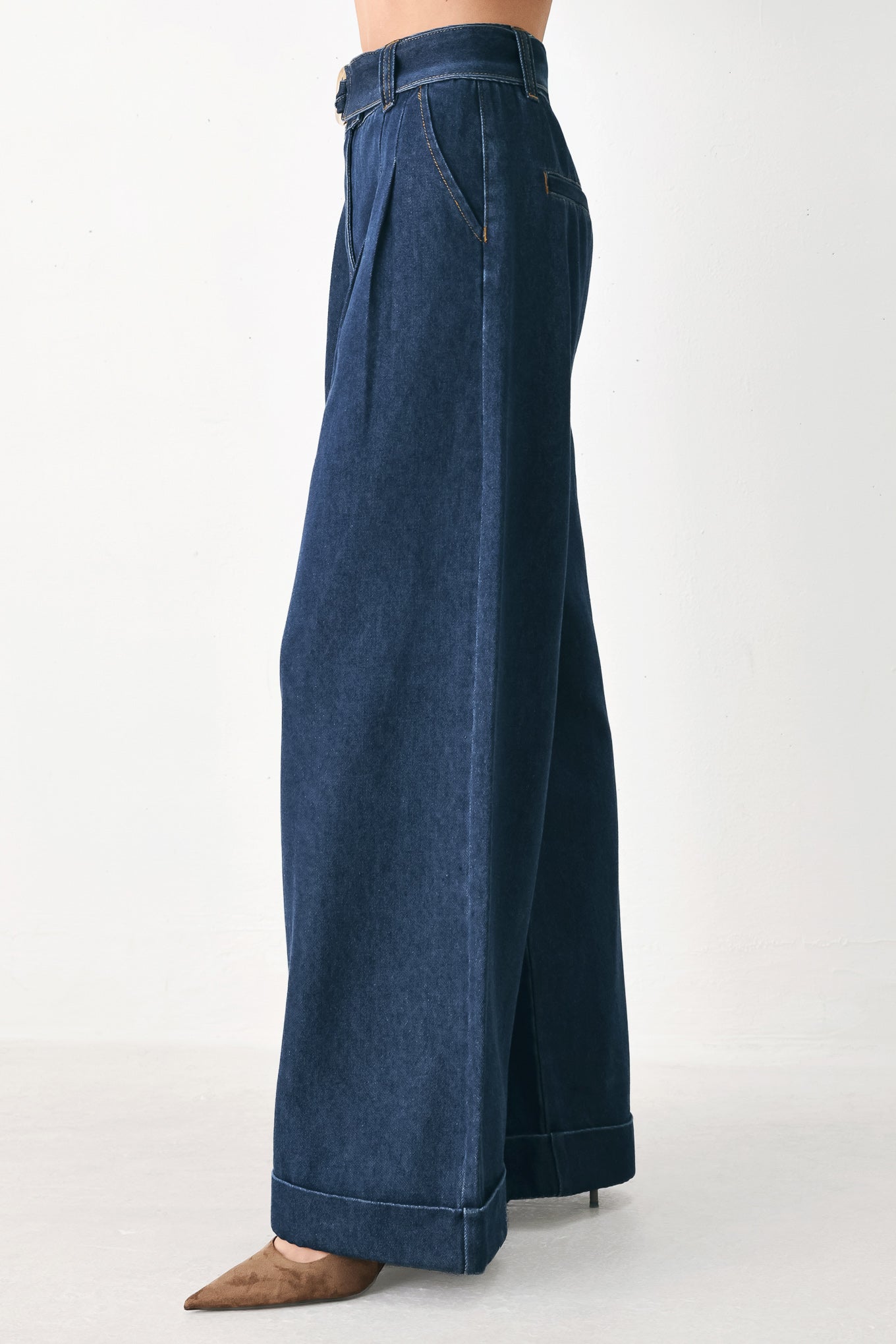 A person wearing dark blue wide-leg denim pants with a rolled cuff and a gold-tone belt buckle | FREEMARKET