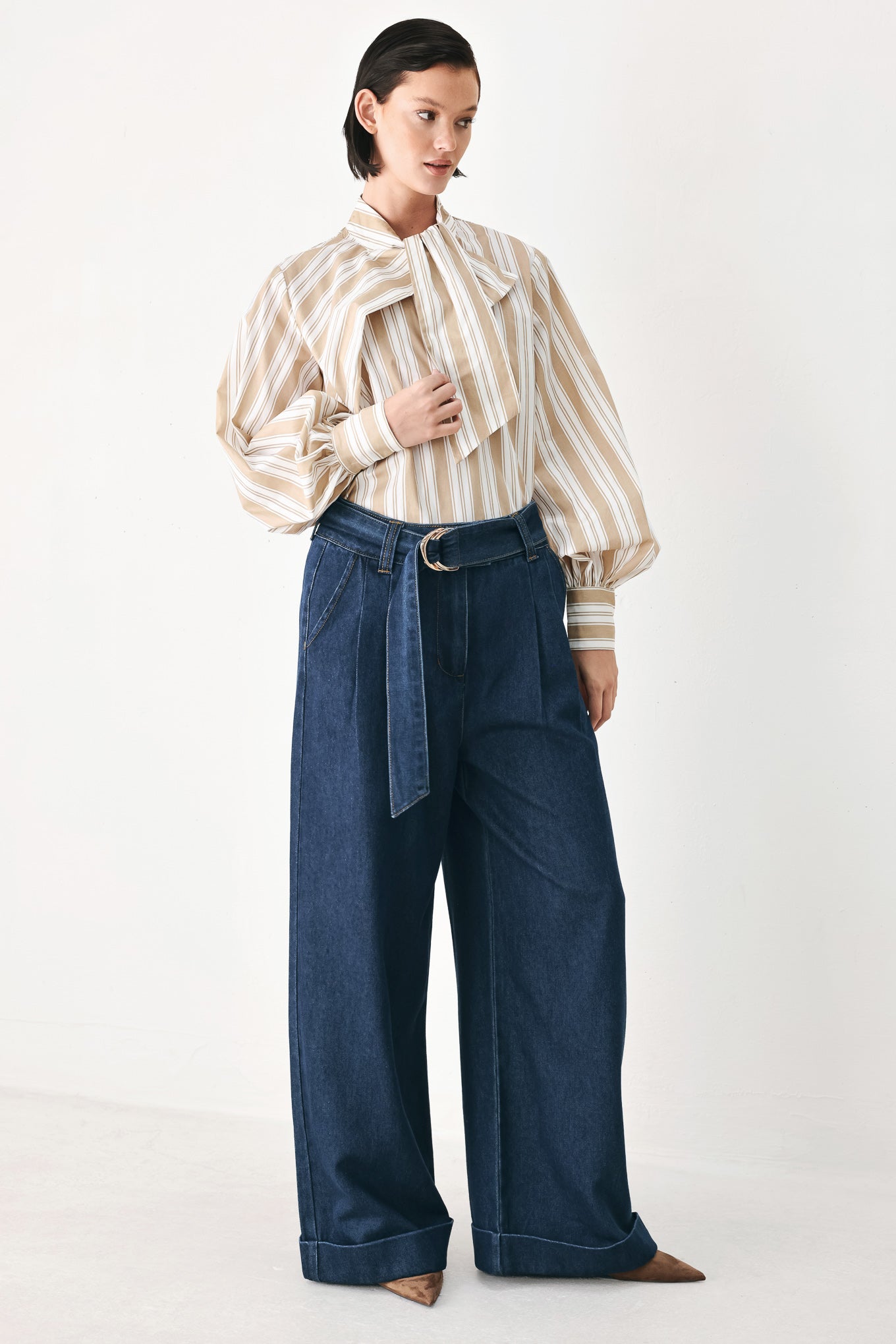 A person wearing dark blue wide-leg denim pants with a rolled cuff and a gold-tone belt buckle | FREEMARKET