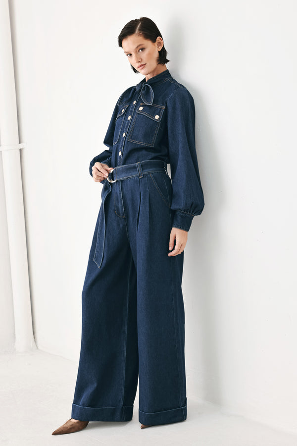A person wearing dark blue wide-leg denim pants with a rolled cuff and a gold-tone belt buckle | FREEMARKET