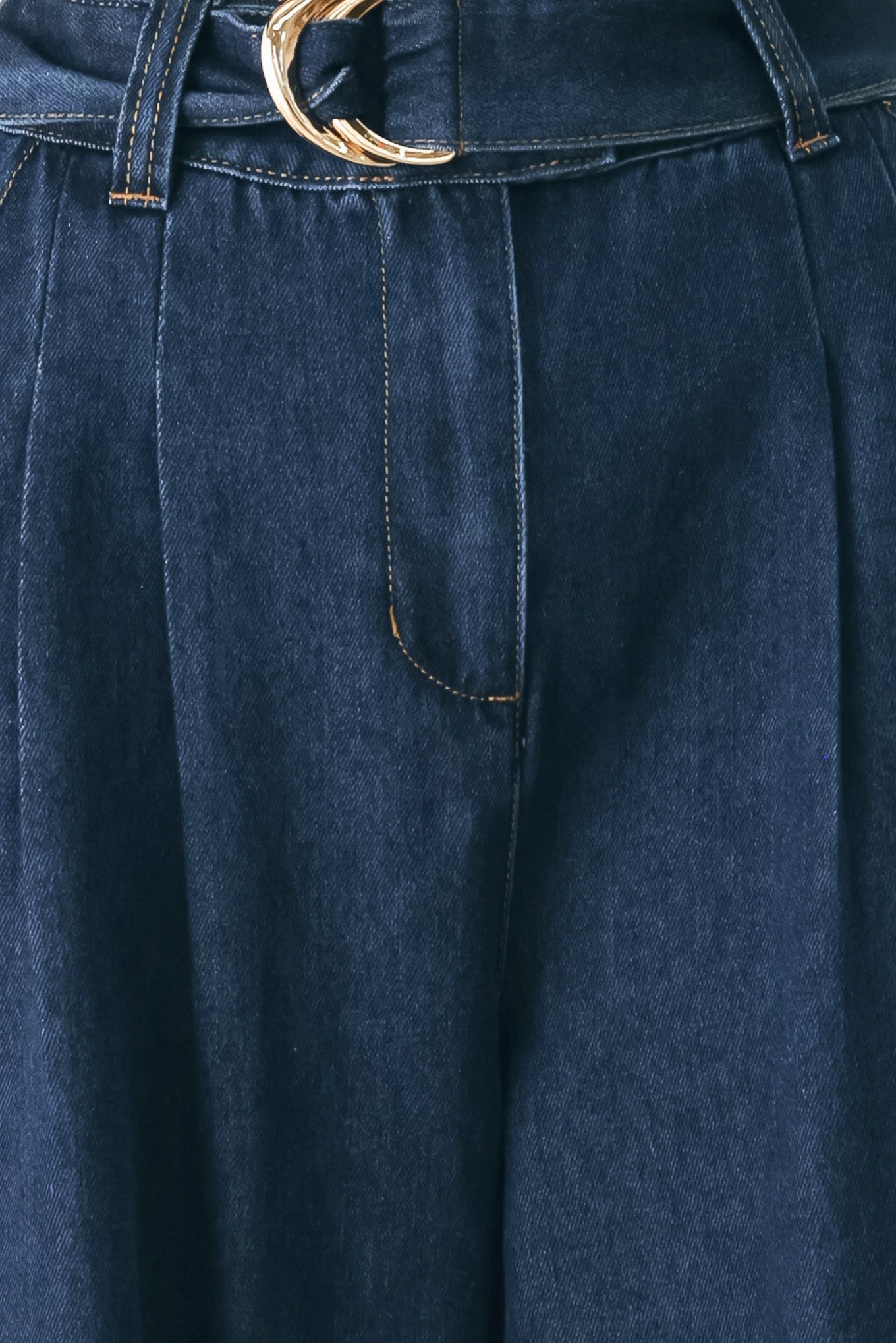 A person wearing dark blue wide-leg denim pants with a rolled cuff and a gold-tone belt buckle | FREEMARKET